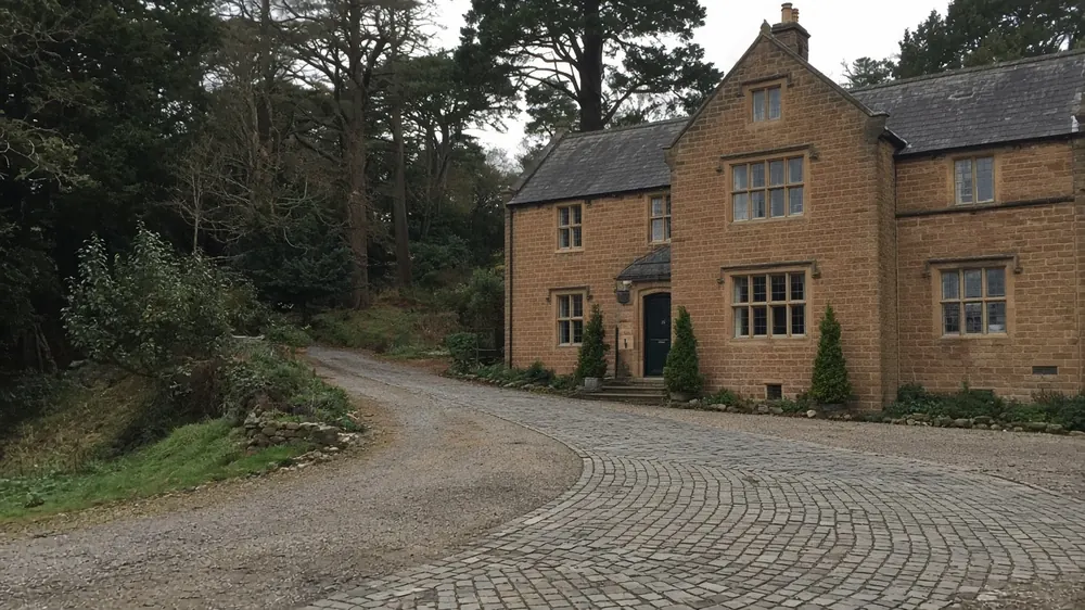Example image: a wide gravel drive with turning area at a stone house